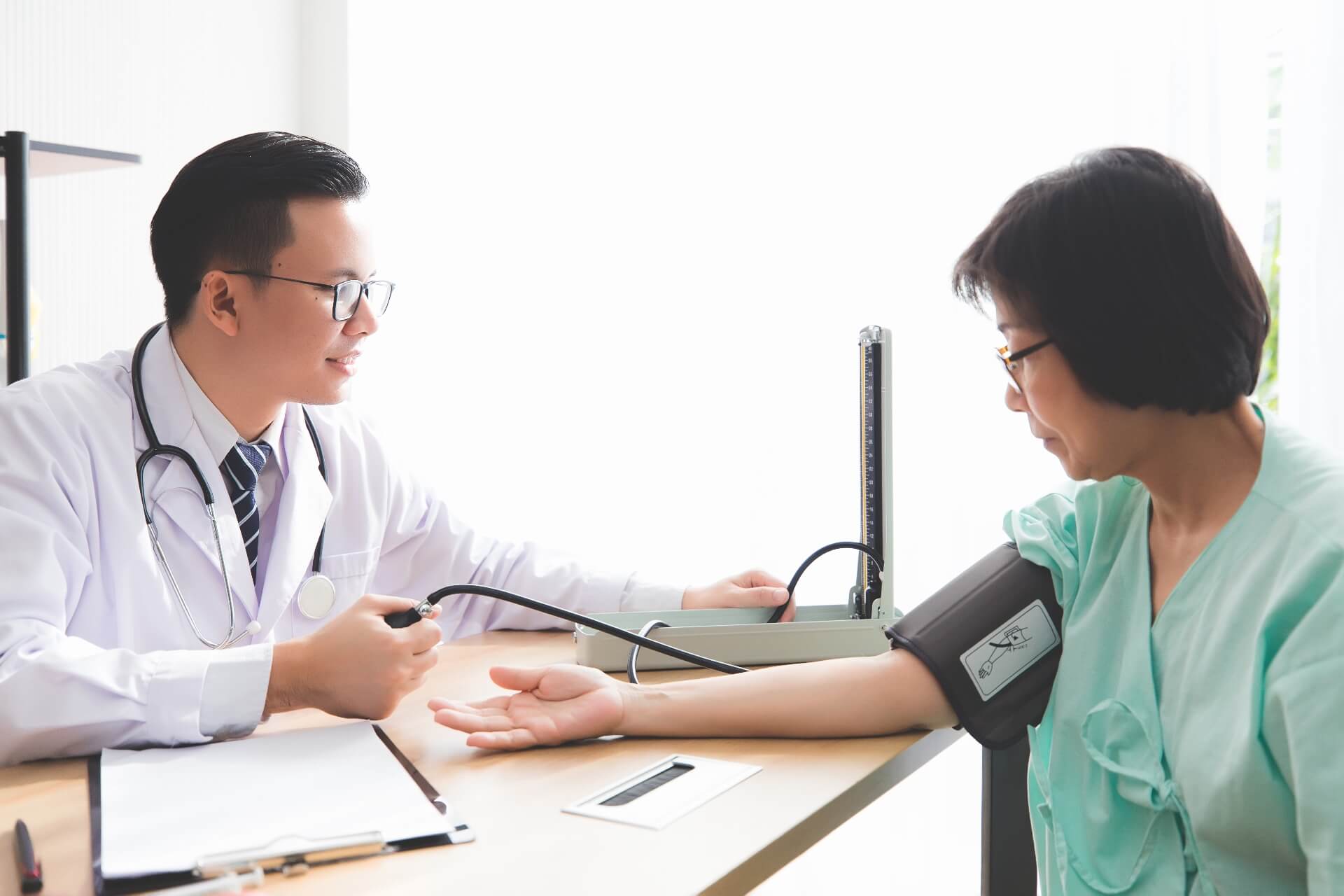 Doctor measuring a middle-aged woman’s blood pressure as part of an annual health check-up.